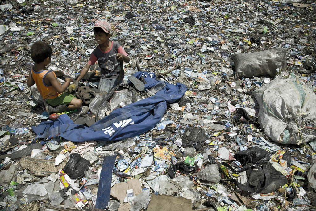 Two kids turn over the garbage looking for plastic or another valued material. Makkasar dump. Indonesia.